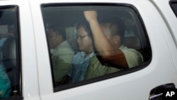 Ny Chakrya, center, former ADHOC and a National Election Committee member who worked at the organization, sits in a car and is transported back to an Anti-Corruption Unit, ACU, after a short appearance at Phnom Penh Municipal Court, in Phnom Penh, Cambodia, Saturday, April 30, 2016. Cambodian authorities arrested five human rights workers last Friday on accusations they tried to help cover up a woman's affair with the deputy leader of the opposition Cambodia National Rescue Party. The action is the latest in a series by Prime Minister Hun Sen's government putting legal pressure on its critics and political opponents. (AP Photo/Heng Sinith)