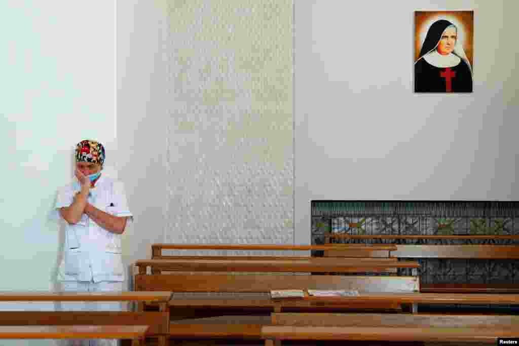 A medical staff member is seen inside the chapel in the San Giovanni hospital before the chaplains bring a cross outside to give a blessing to the medical staff on Good Friday, as Italy is under lockdown to try to stop the spread of coronavirus.
