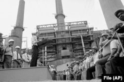 FILE - President Jimmy Carter talks to power plant workers against a backdrop of tall stacks at the Louisville Gas and Electric Company plant in Louisville, Ky., July 31, 1979.