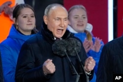 Vladimir Putin gestures while addressing a crowd at a concert marking the 10th anniversary of Russia's annexation of Crimea from Ukraine in Moscow on March 18, 2024.