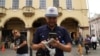 El influente salvadoreño Douglas Guzmán configura su teléfono celular para filmar un video en una plaza de San Salvador el 24 de junio de 2023.