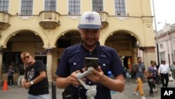 El influente salvadoreño Douglas Guzmán configura su teléfono celular para filmar un video en una plaza de San Salvador el 24 de junio de 2023.