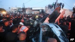 FILE - Palestinians surround a car that was hit by an Israeli airstrike in Rafah, Gaza Strip, January 20, 2024