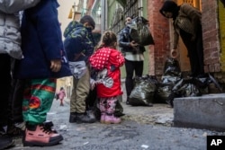 Children and their families wait their turn as coats and shoes are handed out by volunteers in the Tarlabasi neighborhood in Istanbul, Turkey, Dec. 14, 2024.