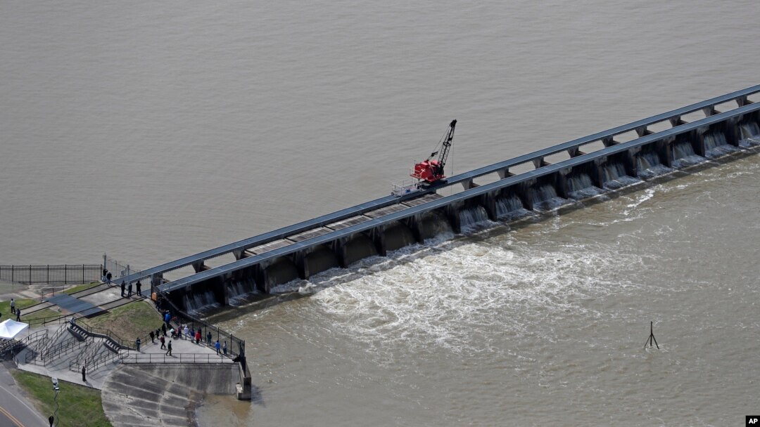 FILE - Workers open the gates of the Bonnet Carre spillway, a river diversion structure, which diverts water from the rising Mississippi River, left, to Lake Pontchartrain, in Norco, La., March 8, 2018.