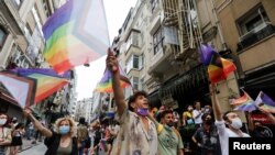 FILE - Demonstrators march with rainbow flags as they try to gather for a Pride parade, which was banned by local authorities, in central in Istanbul, Turkey, June 26, 2021.