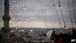 FILE—Mahya master Cemil Buyurkan installs lights at the top of one of the minarets of the Suleymaniye mosque in Istanbul, Turkey, March 6, 2024.