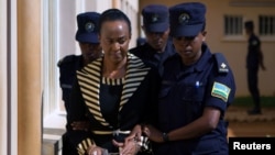 Adeline Rwigara, mother of Diane Shima Rwigara, a prominent critic of Rwanda's President Paul Kagame, is escorted by police officers into a courtroom in Kigali, Rwanda, Oct. 11, 2017.