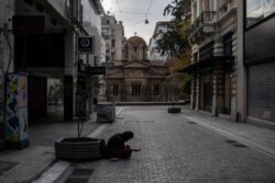 A beggar sits in an empty Ermou street in front of Kapnikarea church during lockdown measures by the Greek government to prevent the spread of coronavirus in Athens, April 21, 2020.