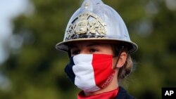 A firefighter wears a face mask with the colors of the French flag, prior to the Bastille Day parade, July 14, 2020 on the Champs Elysees avenue in Paris.