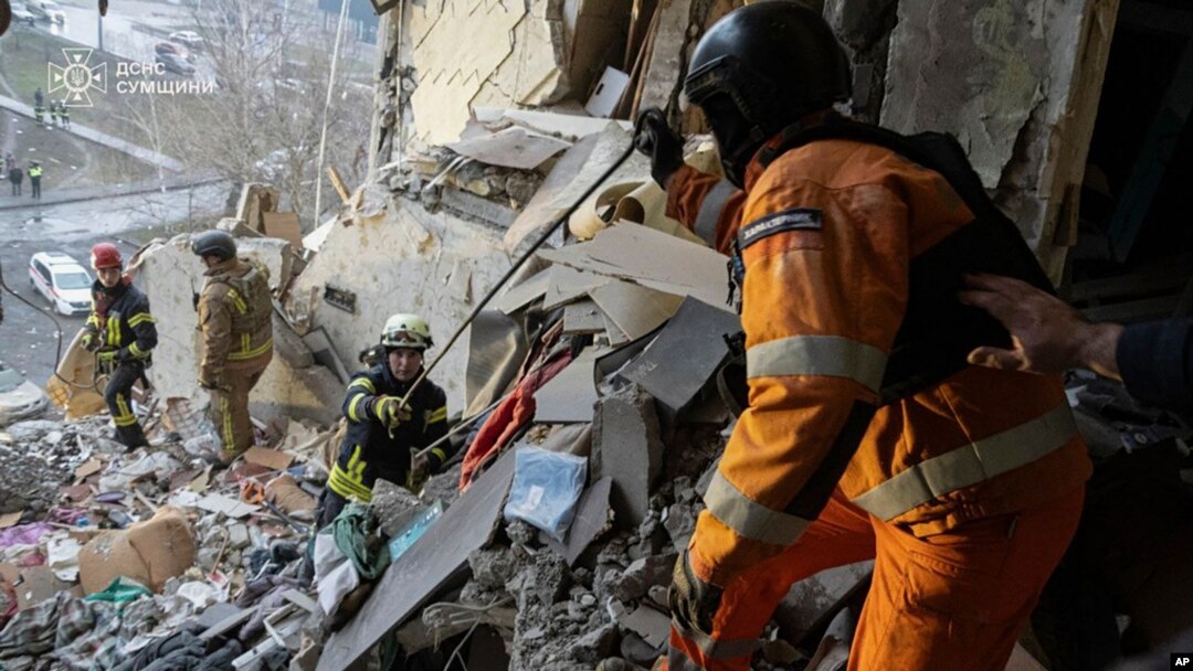 In this photo provided by the Ukrainian Emergency Service, rescuers search for the dead and injured after a Russian drone hit an apartment building in Sumy, Ukraine, Jan. 30, 2025. 