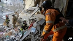 In this photo provided by the Ukrainian Emergency Service, rescuers search for the dead and injured after a Russian drone hit an apartment building in Sumy, Ukraine, Jan. 30, 2025. 