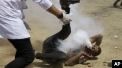 FILE - Palestinian medic rushes to a a protester who got shot in his mouth by teargas canister fired by Israeli troops near the Gaza Strip's border with Israel, east of Khan Younis, in the Gaza Strip, June 8, 2018. 