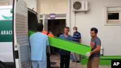 People upload coffins with the bodies of migrants who were drowned while they were trying to cross on a boat to the nearby Greek island of Kos, in the coastal town of Bodrum, Turkey, Sept. 27, 2015.