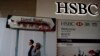 Des passants devant un panneau vandalisé près d'une succursale de la banque HSBC endommagée par des manifestants pro-démocratie à Hong Kong, le 4 janvier 2020. (AP)