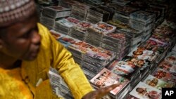 FILE - In this photo on February 19, 2019, a shopkeeper sits by the piles of Hausa-language DVDs he sells in the market in Kano. Some in the popular Hausa-language film industry known as Kannywood have shot music video appealing to the country for peaceful elections.