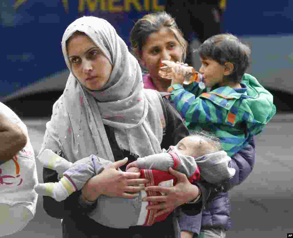 A woman carries her child as they arrive at the main train station in Munich, Germany, Sept. 5, 2015. 