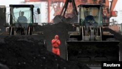 FILE - An employee walks between front-end loaders, which are used to move coal imported from North Korea at Dandong port in the Chinese border city of Dandong, Liaoning province Dec. 7, 2010.