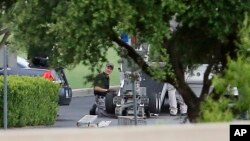 FILE - Police appear to setup a remotely operated robot during a stand off in Hutchins, Texas, June 13, 2015