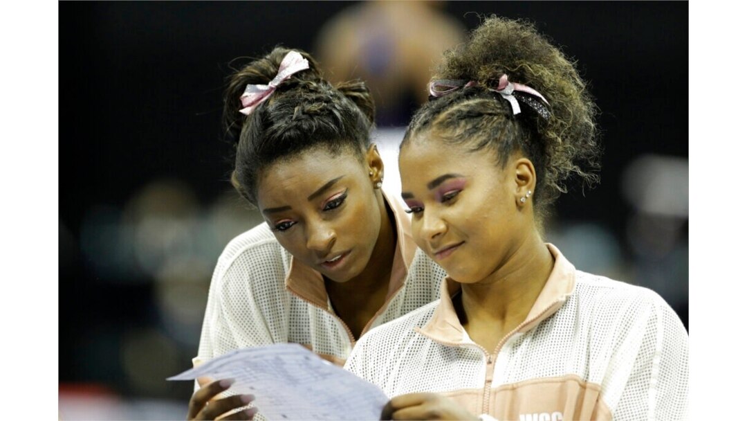 FILE - Simone Biles, left, and Jordan Chiles look over a rotation schedule during practice for the senior women's competition at the 2019 U.S. Gymnastics Championships, in Kansas City, Mo., Aug. 11, 2019.
