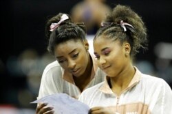 FILE - Simone Biles, left, and Jordan Chiles look over a rotation schedule during practice for the senior women's competition at the 2019 U.S. Gymnastics Championships, in Kansas City, Mo., Aug. 11, 2019.