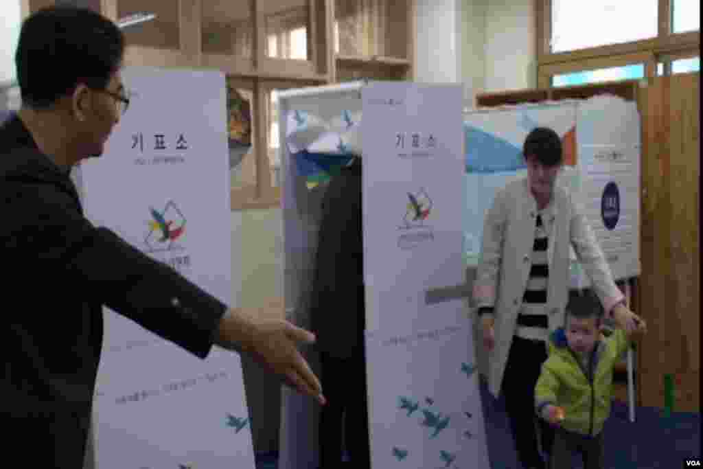 A mother and child approach the voting booth.