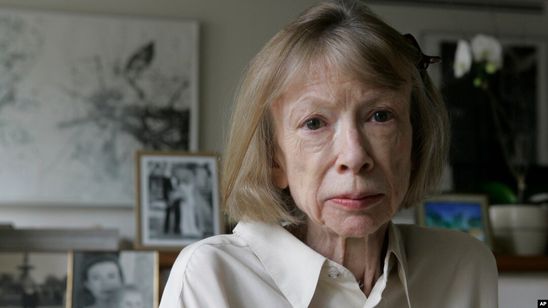 FILE - Author Joan Didion sits in front of a photo of herself holding her daughter, Quintana Roo, and another picture of her daughter's wedding, in her New York apartment Sept. 26, 2005. 