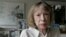 FILE - Author Joan Didion sits in front of a photo of herself holding her daughter, Quintana Roo, and another picture of her daughter's wedding, in her New York apartment Sept. 26, 2005. 