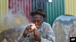 FILE - Reggae legend Bunny Wailer smokes a pipe stuffed with marijuana after Jamaica lawmakers passed an act to decriminalize small amounts of pot, Aug. 28, 2014.