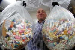 In this Wednesday, Sept. 11, 2019, file photo, narcotics detective Ben Hill, with the Barberton Police Department, shows two bags of medications that are are stored in their headquarters and slated for destruction in Barberton, Ohio.