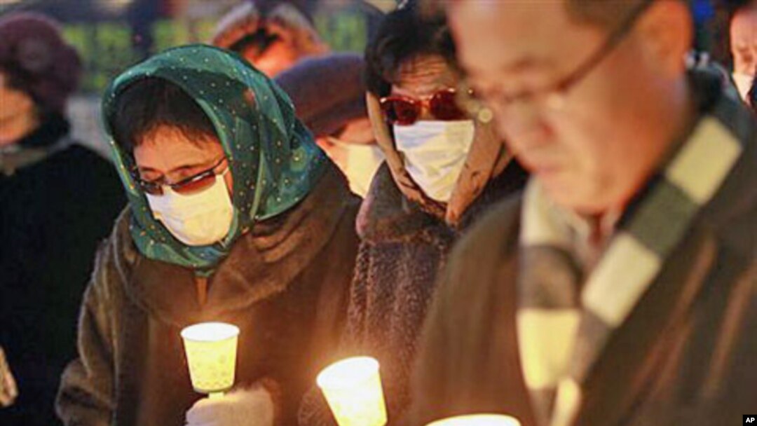 Former North Korean defectors, wearing masks to cover their identities, pay silent tribute during a rally for victims from North Korea's attack and freedom, human rights for North Korean, in Seoul, South Korea, December 20, 2010
