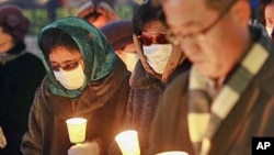 Former North Korean defectors, wearing masks to cover their identities, pay silent tribute during a rally for victims from North Korea's attack and freedom, human rights for North Korean, in Seoul, South Korea, December 20, 2010