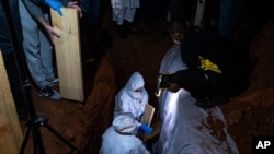 A Muslim burial of a COVID-19 victim takes place at the Westpark Cemetery in Johannesburg late Sunday, June 27, 2021. South Africa has reintroduced tough restrictions including a ban on alcohol sales and an extended nightly curfew as it fights a…