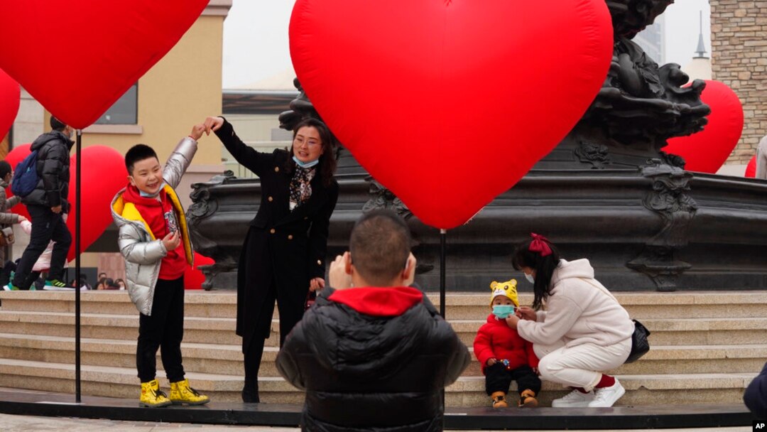 FILE - Families with young children pose for photos in Beijing, China, Feb. 13, 2021. Struggling with an aging population and declining birth rates, China is trying to shift its population policies to avert a demographic crisis.