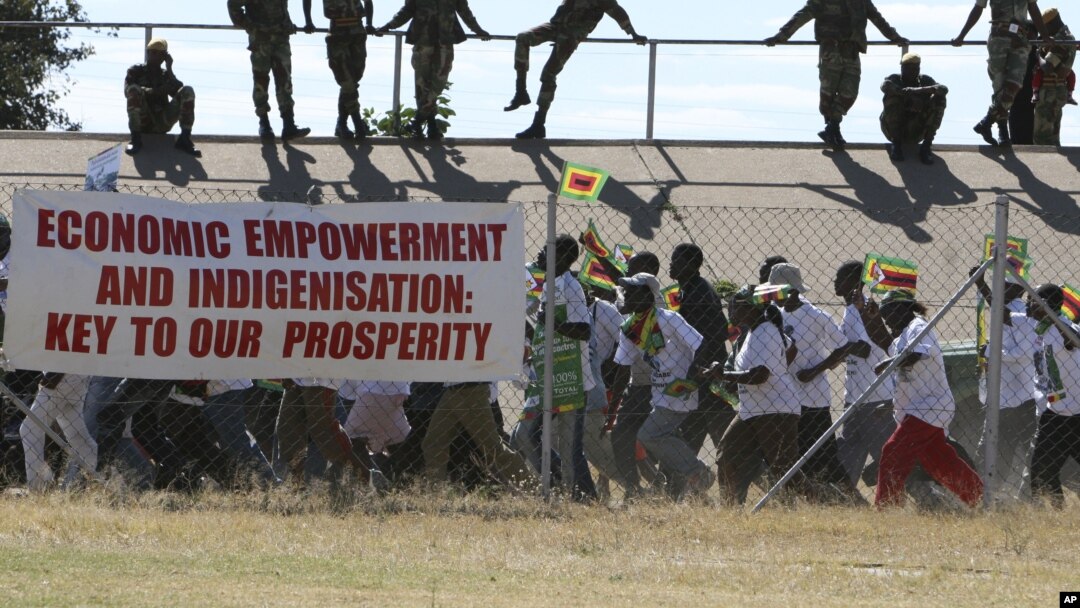 Zimbabwean soldiers lookon as Zanu pf youths march for President Robert Mugabe at a rally in Bulawayo, June 20, 2008. Mugabe who faces Morgan Tsvangirai in a run off election set for June 27 warned Zimbabweans not to vote for the opposition as this would