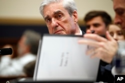 Former special counsel Robert Mueller, checks pages in the report as he testifies before the House Judiciary Committee hearing on his report on Russian election interference, on Capitol Hill, July 24, 2019 in Washington.