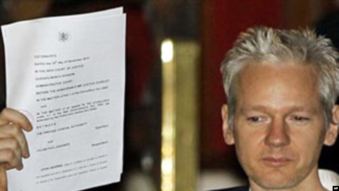 WikiLeaks founder Julian Assange holds up a court document for the media after he was released on bail, outside the High Court, London, 16 Dec 2010