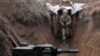 FILE - An Ukrainian serviceman walks in a trench as he stands at his post on the frontline with Russia-backed separatists near the town of Zolote, in the Lugansk region, April 8, 2021. 