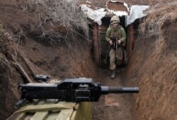 An Ukrainian serviceman walks in a trench as he stands at his post on the frontline with Russia backed separatists near the town of Zolote, in the Lugansk region on April 8, 2021.