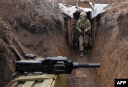An Ukrainian serviceman walks in a trench as he stands at his post on the frontline with Russia backed separatists near the town of Zolote, in the Lugansk region on April 8, 2021.