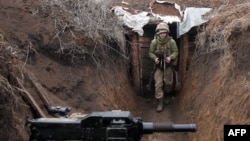 FILE - An Ukrainian serviceman walks in a trench as he stands at his post on the frontline with Russia-backed separatists near the town of Zolote, in the Lugansk region, April 8, 2021. 