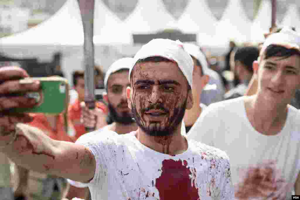 Seorang pria mengambil swafoto dalam ritual Ashura di Nabatieh, Lebanon. (VOA/J. Owens)