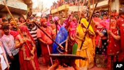 Indian women from Barsana village beat a villager from Nandgoan with wooden sticks as he teases them during Lathmar holi festival celebrations at the legendary hometown of Radha, consort of Hindu god Krishna, in Barsana.