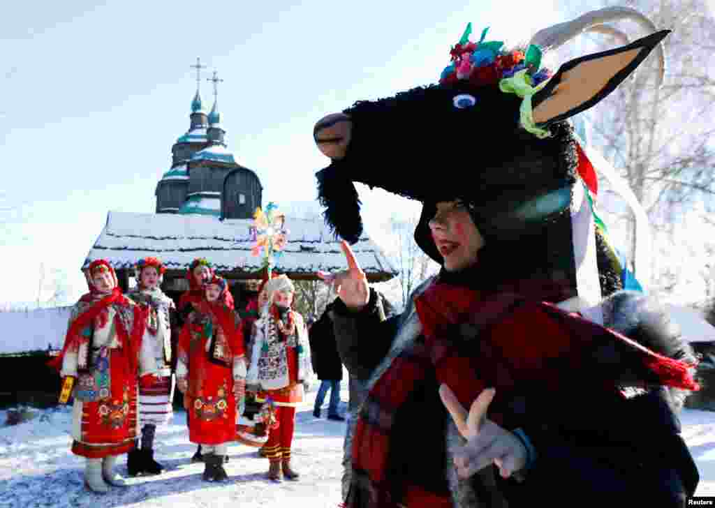 Warga Kristen Ortodoks yang mengenakan kostum tradisional menyanyikan lagu-lagu Natal saat mereka merayakan hari Natal Ortodoks di kompleks museum Arsitektur Nasional di Kyiv, Ukraina, Jumat (7/1). (Foto: Reuters)