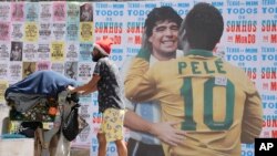Un hombre empuja un carrito lleno de basura para reciclar frente a un mural en el que se muestra al astro brasileño Pelé abrazando a la difunta estrella del fútbol, el argentino Diego Maradona, en Sao Paulo, Brasil, el 24 de diciembre de 2022. 