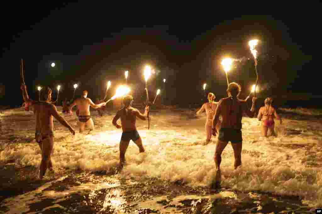 Socorristas se meten en el océano Atlántico con antorchas en una ceremonia para conmemorar el Día del Socorrista, para honrar su compromiso con la seguridad y los rescates, en Mar Azul, Argentina, el 14 de febrero de 2025.