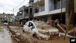 A car parked outside a building is swamped in mud, in Kathmandu, Nepal, Sept. 30, 2024, in the aftermath of flooding caused by heavy rains. 