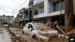 Sebuah mobil yang terparkir di luar sebuah gedung di Kathmandu, Nepal, tampak diselimuti lumpur pada 30 September 2024, menyusul banjir yang menerjang wilayah tersebut. (Foto: AP/Gopen Rai)