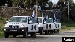 United Nations peacekeepers put on protective gear before driving through the Kuneitra border crossing between Israel and Syria, in the Israeli occupied Golan Heights, March 8, 2013.