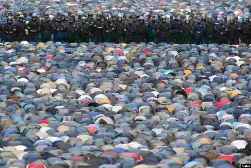 Russian Interior Ministry members stand guard as Muslims attend an Eid al-Adha mass prayer in Moscow, Oct. 4, 2014.